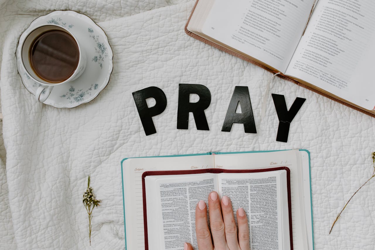 Flat lay of morning prayer routine including Bible, coffee, and PRAY letters.